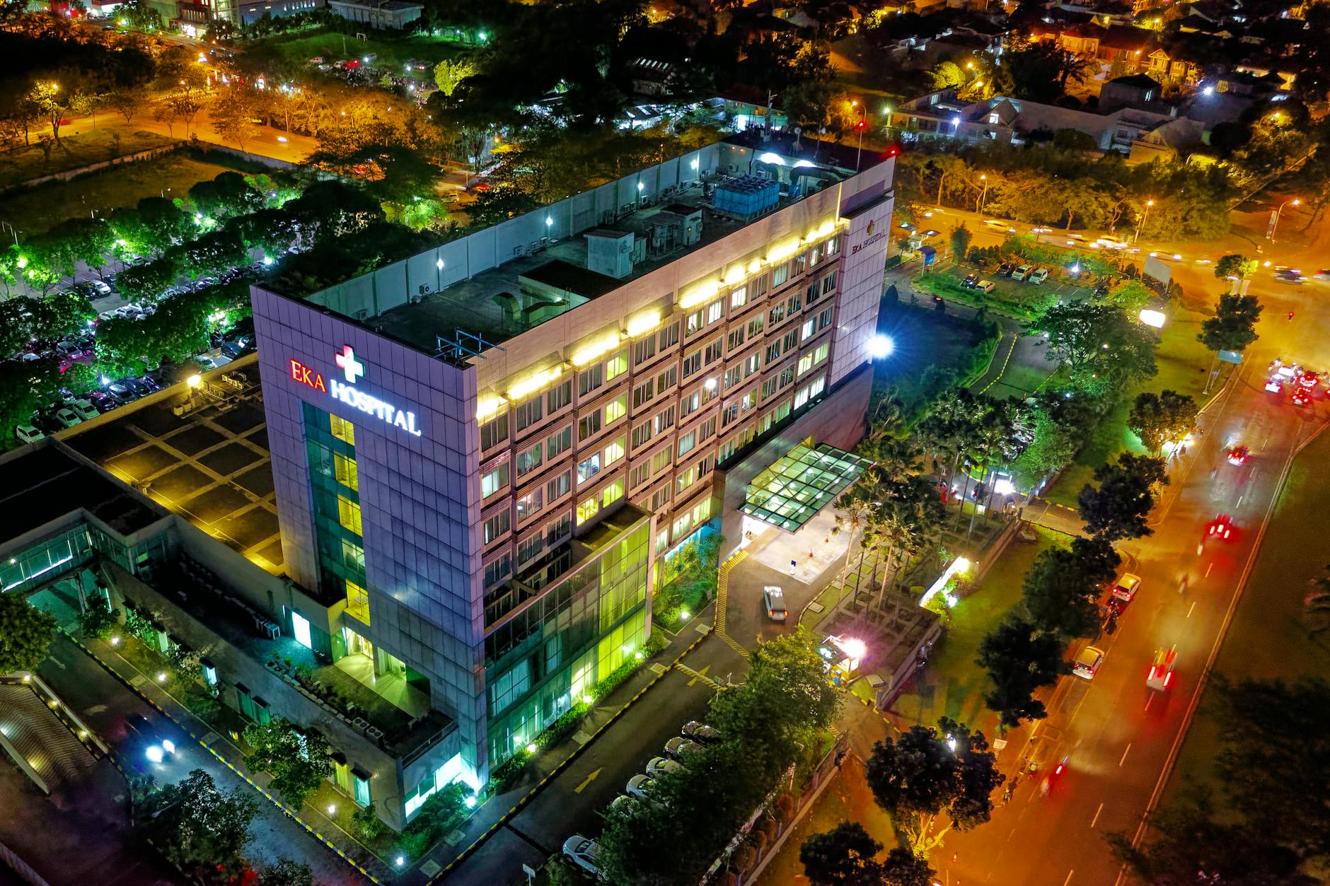 hospital beside vehicle park and road at night